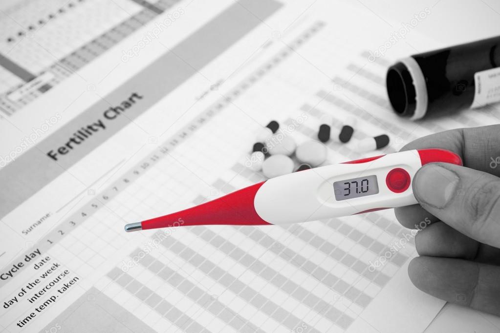 Red thermometer on black and white fertility composition