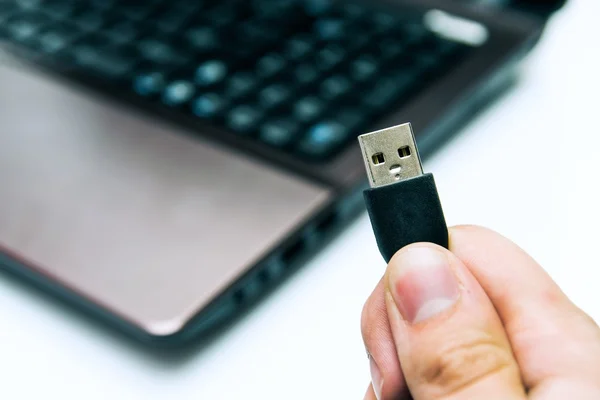 Człowiek posiadający złącze USB. laptop w tle — Zdjęcie stockowe