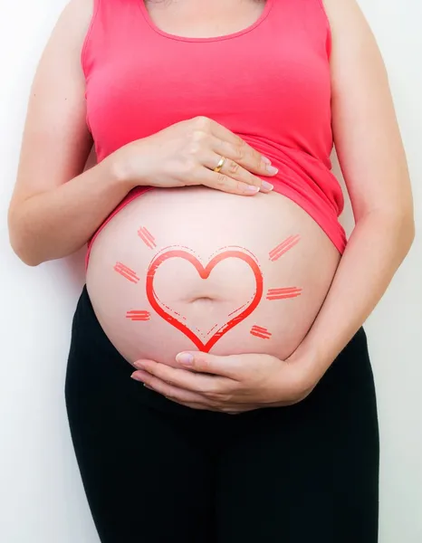 Pregnant woman with the drawn heart on a belly — Stock Photo, Image