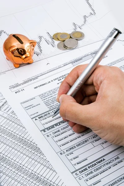 Man hand filling PIT-11 income tax forms with piggybank and coin — Stock Photo, Image