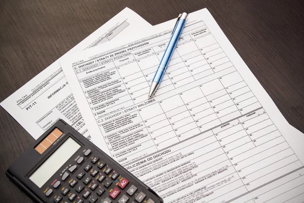 Steuerformular mit Stift und Taschenrechner auf dem Schreibtisch polieren — Stockfoto
