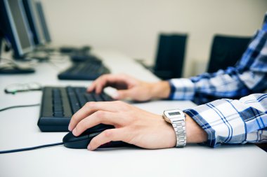 Young man typing on keyboard. Training room with computers clipart
