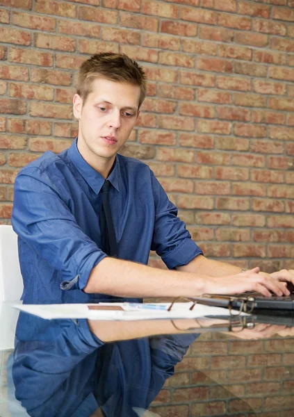 Jovem empresário sentado à mesa e trabalhando com gráficos — Fotografia de Stock