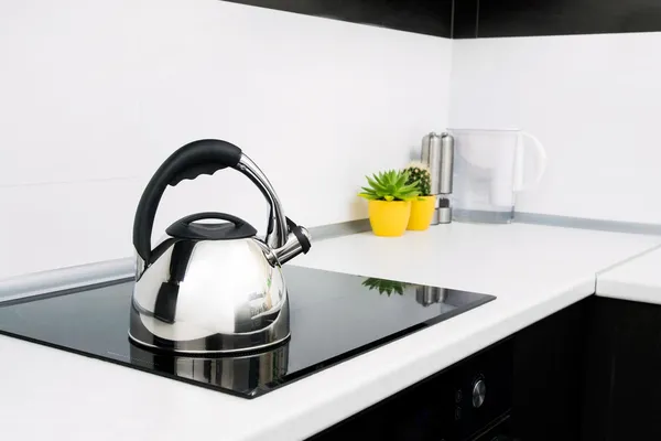 Steel kettle in modern kitchen with induction stove — Stock Photo, Image