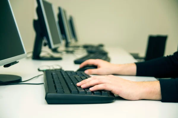 Young man typing on keyboard. Training room with computers — Stock Photo, Image