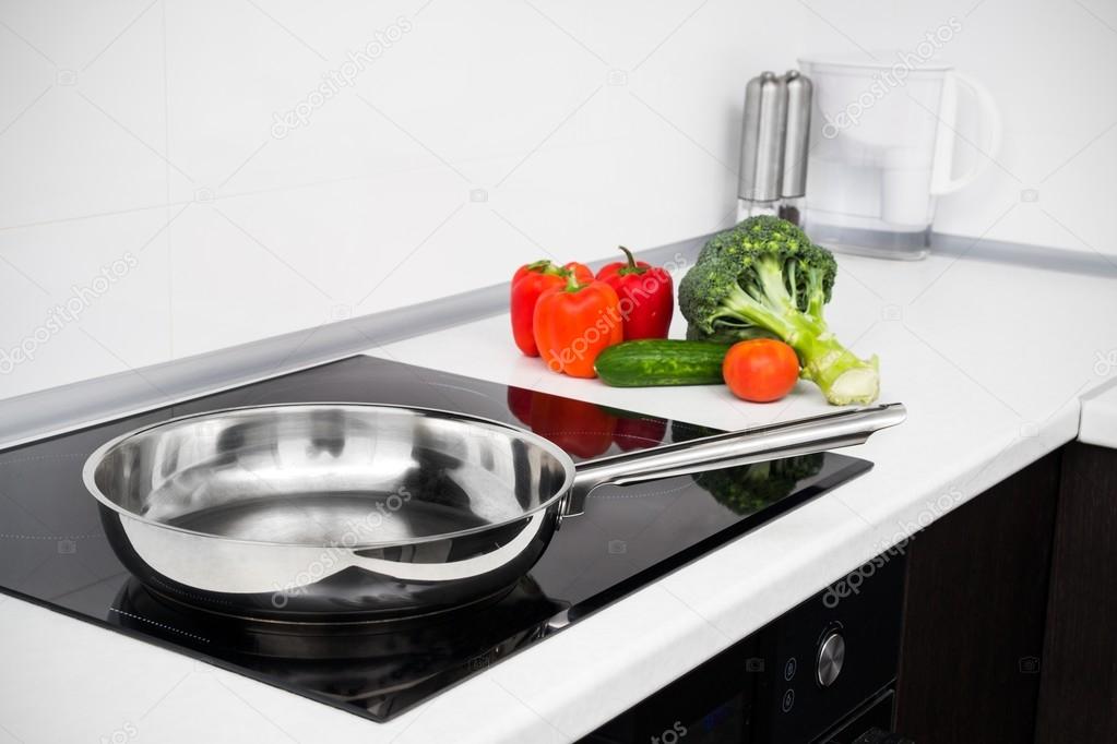 Foto de bodegón de cacerolas de metal en la estufa de inducción en la cocina