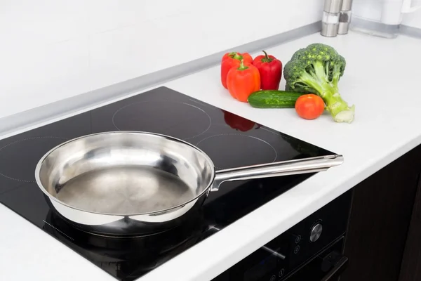 Frying pan and vegetables in modern with induction stove — Stock Photo, Image