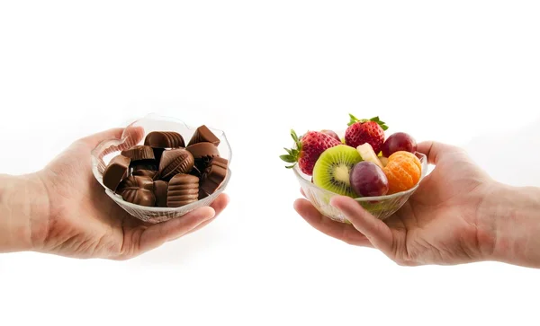 Elija alimentos saludables. Cuenco con chocolates y un tazón de fruta —  Fotos de Stock