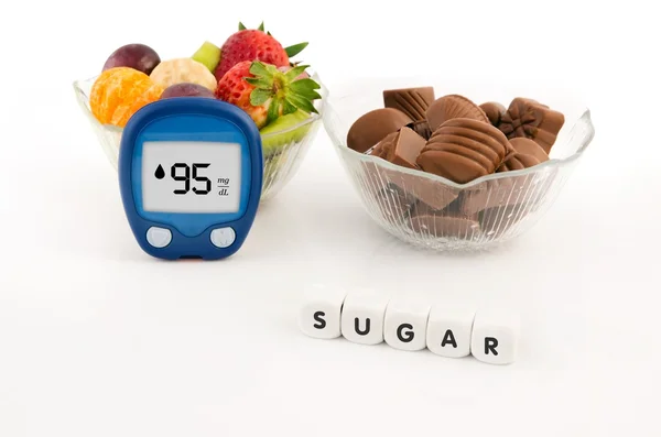 Glucometer and bowl with chocolates and fruits. Healthy lifestyl — Stock Photo, Image