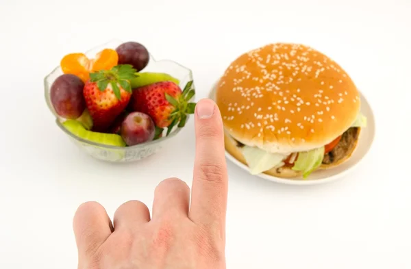 Ujj közötti választás hamburgert és gyümölcsök. élelmiszer-fehér fonákkal — Stock Fotó