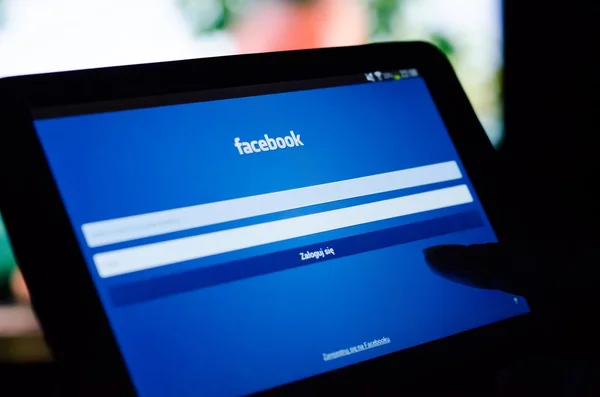 Женщина указывает планшет с мобильным приложением Facebook с польским в том числе — стоковое фото