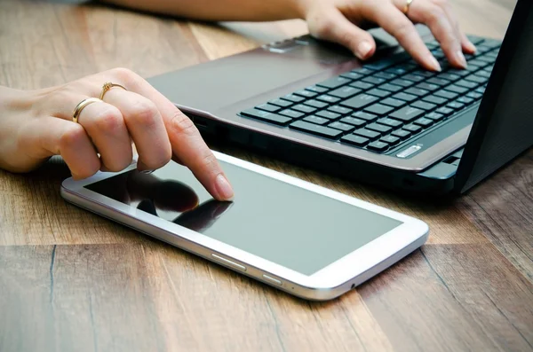 Mujer trabajando con tablet y laptop sobre fondo de madera — Foto de Stock