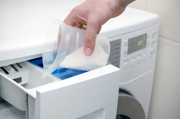 Vrouw hand gieten waspoeder in de wasmachine — Stockfoto