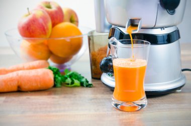 Juicer and carrot juice. Fruits in background clipart
