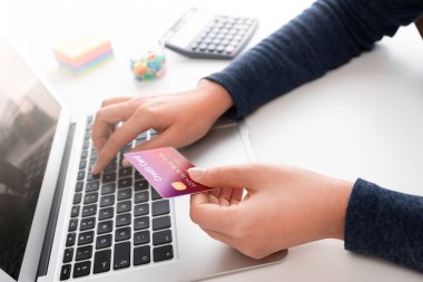 Dizüstü bilgisayar kullanan bir kadın, online alışveriş konsepti, elinde kredi kartı