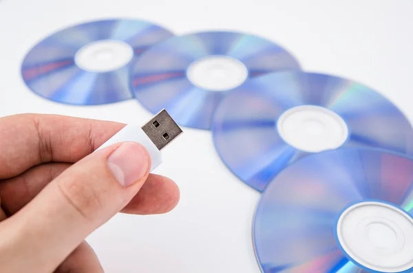 Mão segurando unidade USB. Discos de DVD em segundo plano — Fotografia de Stock