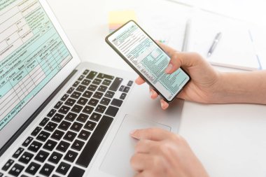 ABD Bireysel Gelir Vergisi İadesi. Amerikan vergi formlarıyla çalışan muhasebeci, akıllı telefon kullanıyor.