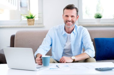 Masada oturan gülümseyen adam. Ev bütçesi, finans kavramı
