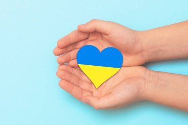 Ukrayna ulusal renkleri taşıyan bir kalbi tutan el. Savaş sırasında Ukrayna 'ya yardım