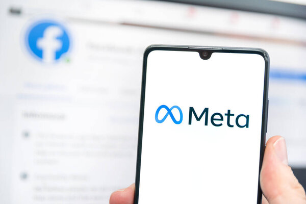 Wroclaw, Poland - APR 01, 2022: Facebook changes its company name to Meta. Meta on a smartphone and Facebook logo in the background
