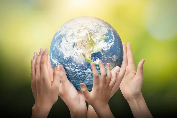 Earth globe in family hands. World environment day concept. Elements of this image furnished by NASA