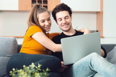 Young couple enjoying internet time, looking in laptop