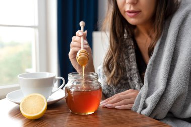 Hasta kadın çayına bal koyuyor.