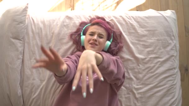 Boldog Tini Lány Rózsaszín Hajjal Fülhallgatót Visel Ágyban Zenét Hallgat — Stock videók