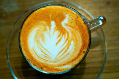 Geç kalmış sanat kahvesi. Yaprak desenli kahve sanatları. Masadaki ya da masadaki temiz fincanda sıcak kahve setini kapat.