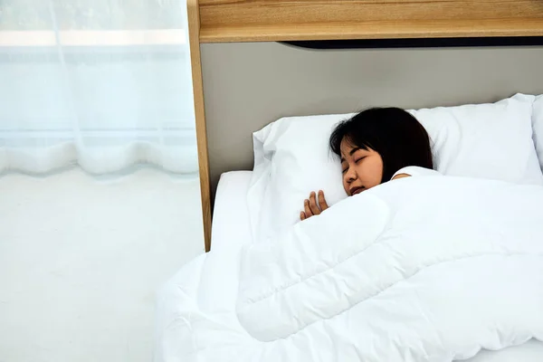 Close up Asian woman sleeping on white bed in the bedroom with sweet dreams and enjoys good rest at home with copy space