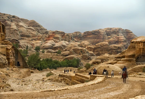 Turisták, gyalog és lóháton, látogatás a Jordániai petra — Stock Fotó