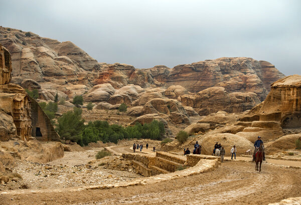 Туристы пешком и на лошадях посещают Петру в Иордании
