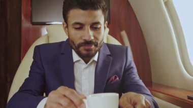 İş adamı özel jette kahve içiyor. Kameraya bakıyorum. Yavaş çekim.