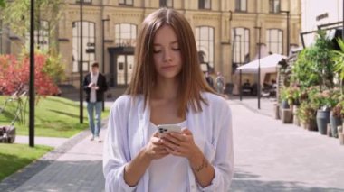 Rahatlamış genç bir kadın caddede yürüyor, etrafa bakıyor. Günün tadını çıkarıyorum. Yavaş çekim.