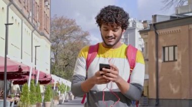 Mutlu ve pozitif genç adam sokakta ayakta ve dans ediyor. Müzik dinlemek ve eğlenmek. Yavaş çekim.