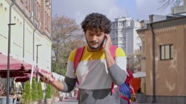 Sokakta yürüyen, müzik dinleyen ve dans eden pozitif bir genç. Gülümsüyor, kameraya bakıyor. Yavaş çekim.