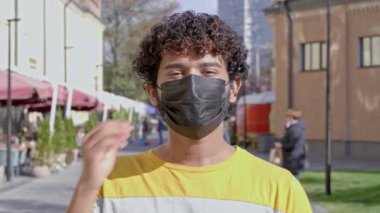 Mutlu ve gülümseyen bir adamın koruyucu maskesini çıkarmasının portresi. Sokakta dikilip kameraya bakıyorum..