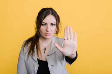 Genç ve güzel bir kadın şakalaşmayı keser, parlak sarı bir arka plan