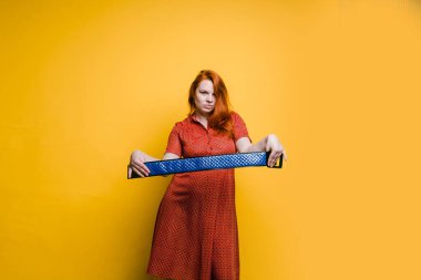 Kırmızı elbiseli, parlak sarı arka planda genç bir kızıl kadın portresi.