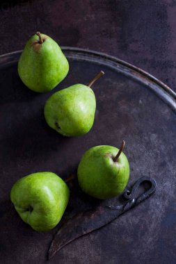Dört yeşil armut Alexander Lucas ve paslı zeminde eski bir bıçak.