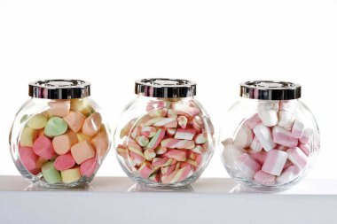 Şeker kavanozlarında marşmelovlar, beyaz tencerelerde izole.