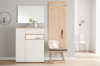 Modern apartman koridorunda ayna ve ahşap depo var.