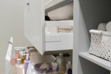 Banyonun içinde kozmetik ürünleri ve hijyen ürünleri olan beyaz açık çekmece.