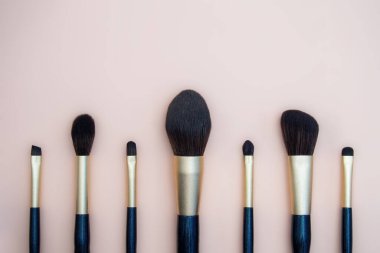 Çeşitli yüz fırçalarından kadın makyajı çeşitleri. Pembe arka planda profesyonel lacivert ve altın rengi makyaj fırçaları..