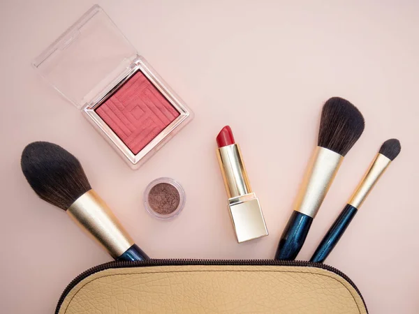 Widok z góry kosmetyki wyróżniające się z beżowym woreczkiem makijażowym na różowym tle — Zdjęcie stockowe