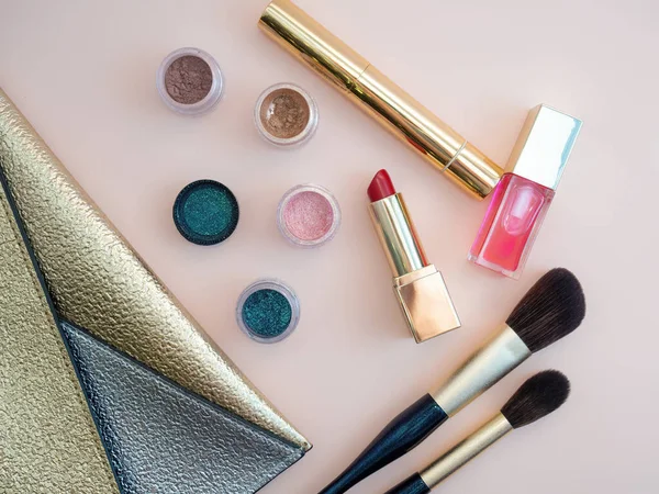 ピンクの背景に金色の化粧バッグから際立つ化粧品のトップビュー — ストック写真