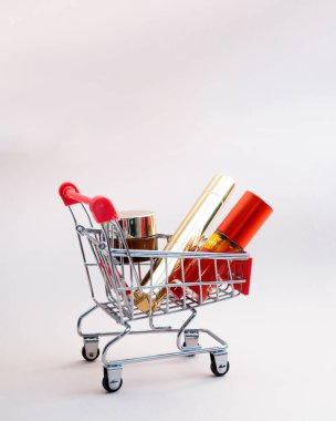 Pembe arka planda makyaj ürünleri olan bir alışveriş arabasının ön görüntüsü. Kozmetik alışveriş konsepti. fotoğraf