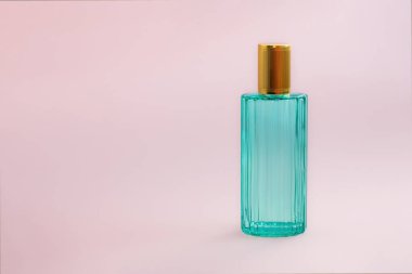 Güzel, modern parfüm şişesi. Yeşil renkli şeffaf camlar ve pembe arka planda altın kapaklı minimalist bir tarz. fotoğraf