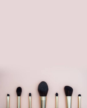 Çeşitli yüz fırçalarından kadın makyajı çeşitleri. Pembe arka planda profesyonel lacivert ve altın rengi makyaj fırçaları. fotoğraf