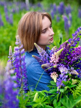 Güzel bir genç kız bir tarlada lupin buketi tutuyor. Doğa ve romantizm kavramı. fotoğraf